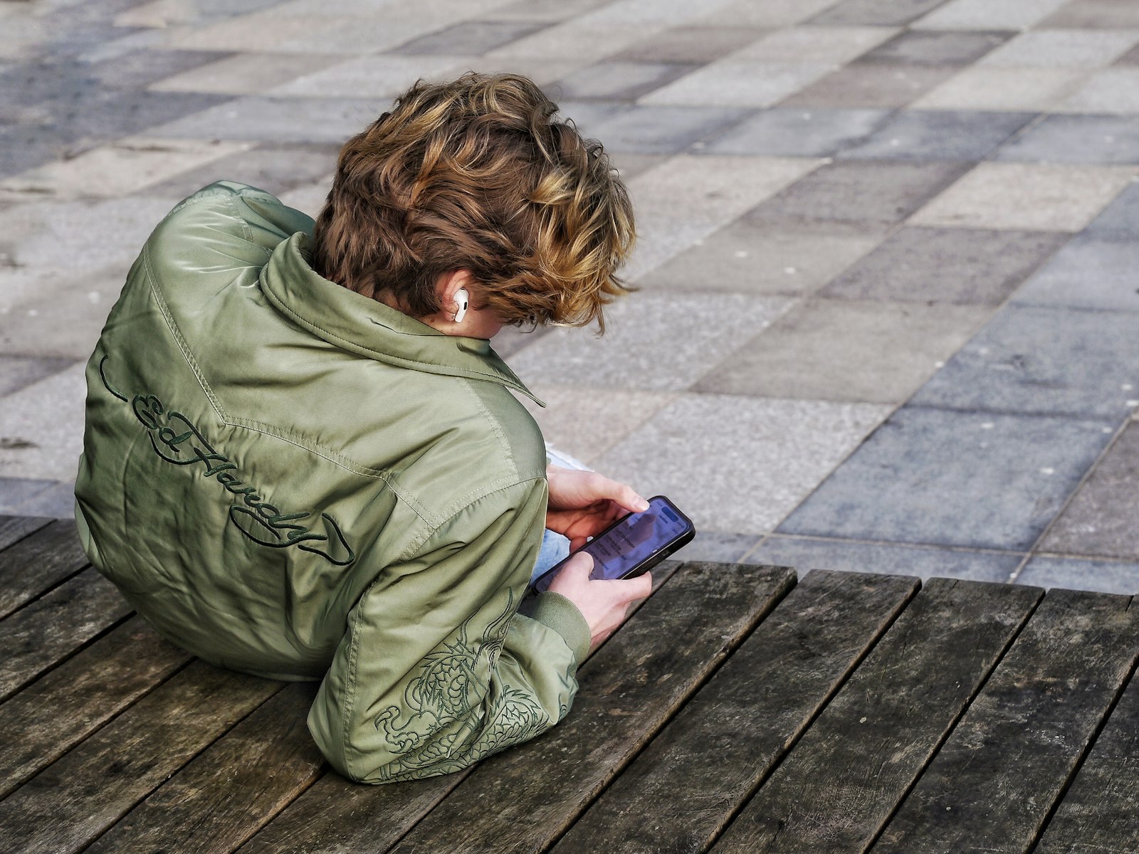 Persoa nova de pelo ondulado usando un teléfono móbil