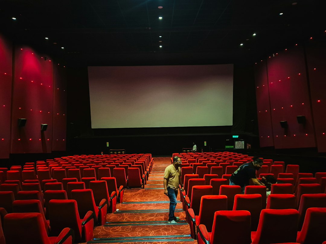 Sala de cine baleira con butacas vermellas e pantalla grande