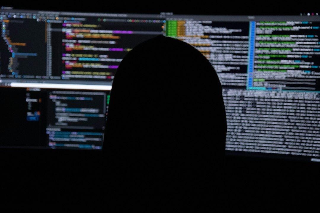 Silueta dunha persoa fronte a varios monitores con liñas de código