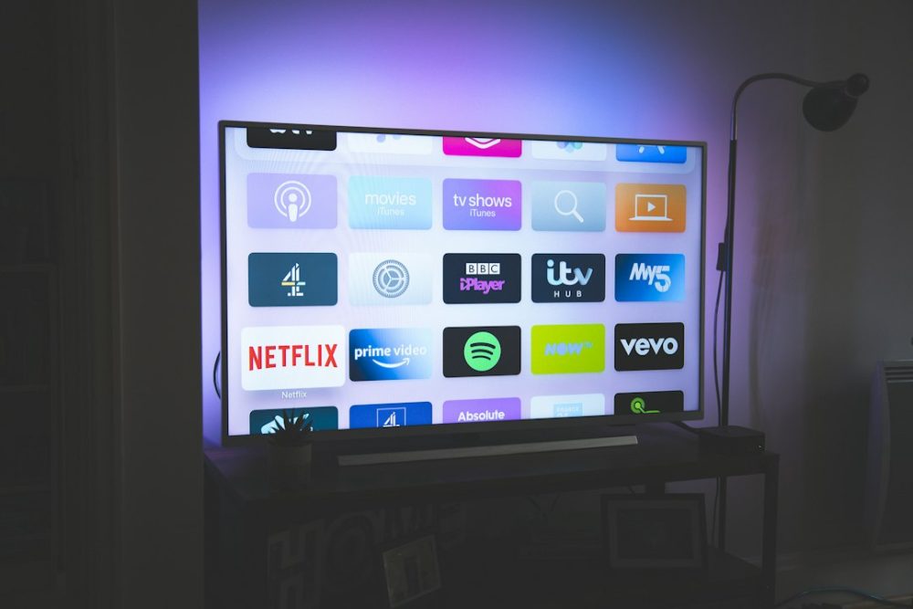Pantalla de televisión cunha grella de iconas de aplicacións de streaming nunha sala escura