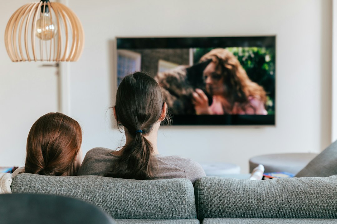 Varias persoas mirando xuntas a televisión no sofá